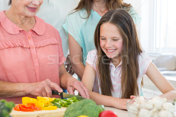 Girl looking at grandmother cutting vegetables Stock photo © wavebreak_media