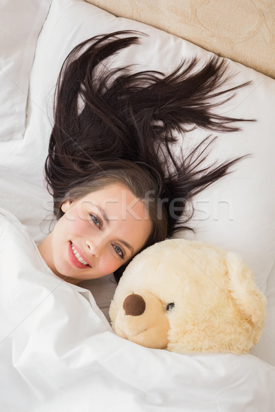 Pretty brunette under the duvet with teddy bear Stock photo © wavebreak_media