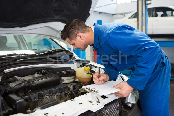 Stock photo: Mechanic examining under hood of car