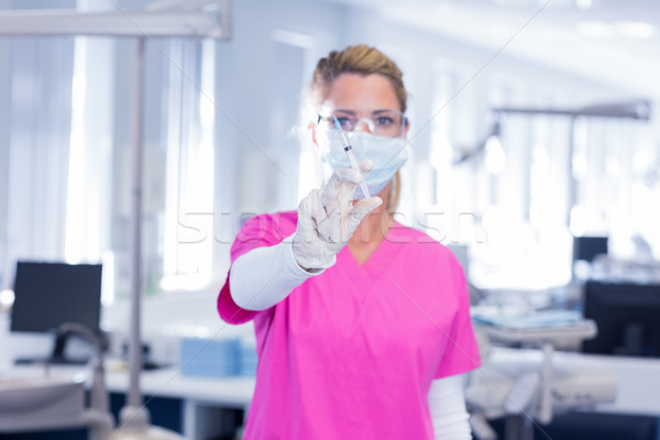 Dentist in surgical mask and scrubs holding syring Stock photo © wavebreak_media
