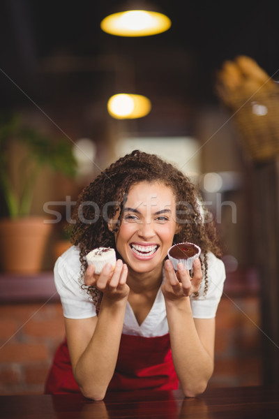 Stock photo: Laughing waitress showing two cupcakes