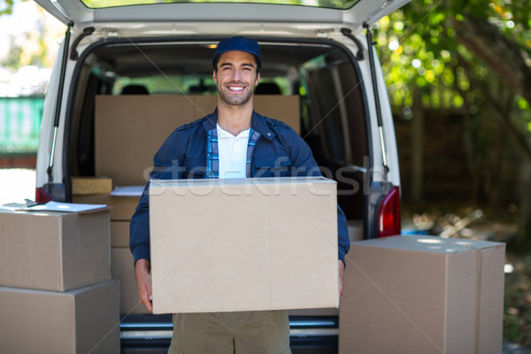 Portrait of smiling delivery man carrying cardboard box Stock photo © wavebreak_media