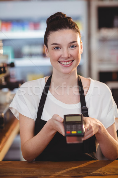 Smiling waitress showing credit card machine Stock photo © wavebreak_media