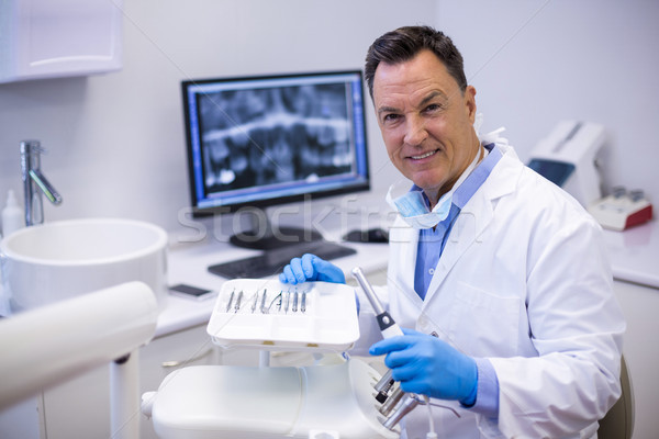 Portrait of smiling dentist holding dental hand piece Stock photo © wavebreak_media