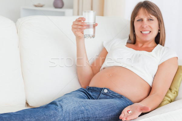 Cute pregnant woman taking a pill while lying on a sofa in her apartment Stock photo © wavebreak_media