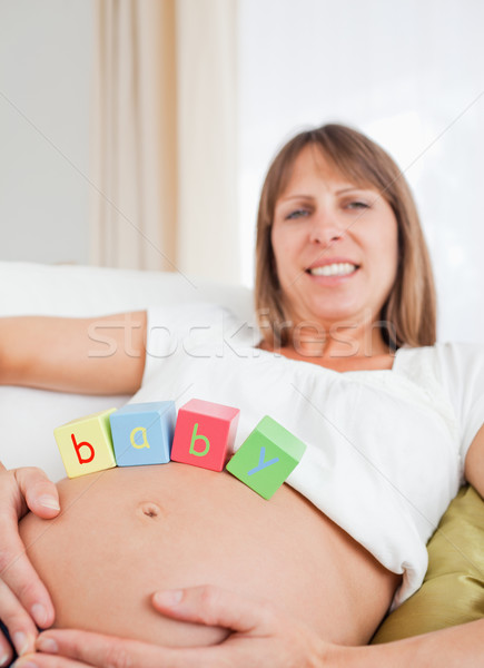 Good looking pregnant female playing with wooden blocks while lying on a sofa in her living room Stock photo © wavebreak_media