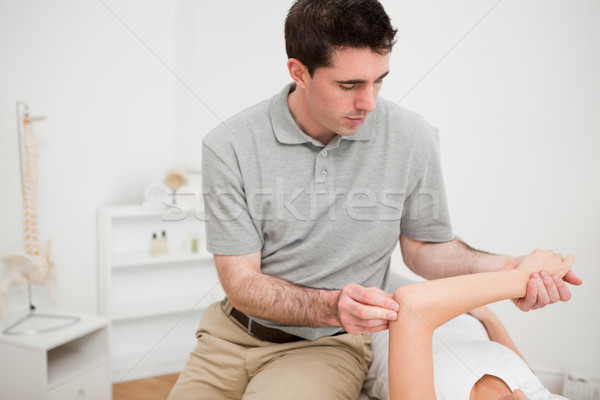 Serious brunette physiotherapist holding the arm of a woman in a room Stock photo © wavebreak_media