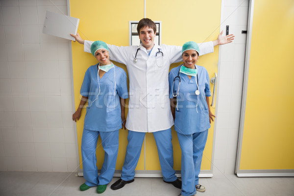 Happy doctor with arms outstretched between two smiling nurses in hospital room Stock photo © wavebreak_media