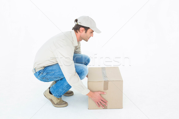 Delivery man crouching while picking cardboard box Stock photo © wavebreak_media