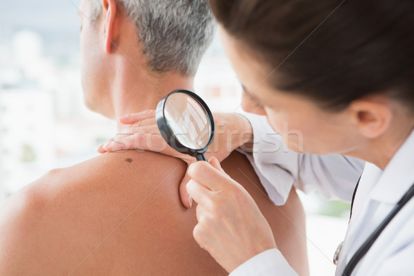 Doctor examining patient with magnifying glass  Stock photo © wavebreak_media