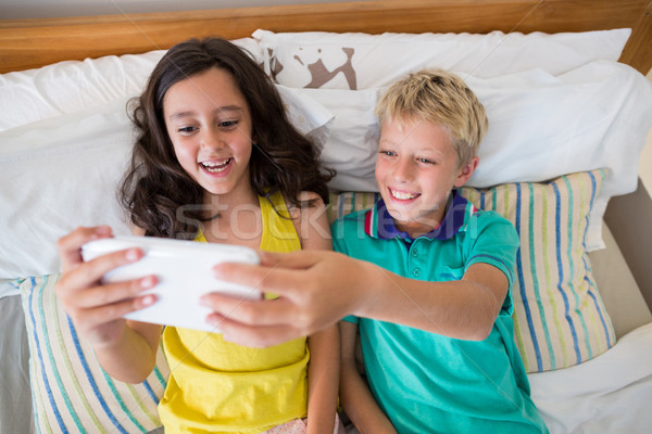 Stock photo: Siblings taking selfie on mobile phone in bedroom