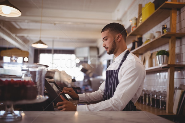 Side view of handsome young waiter using computer at counter Stock photo © wavebreak_media