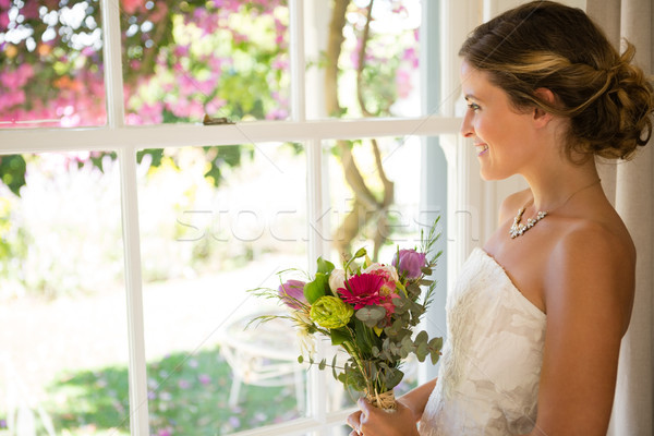 Side view of smiling beautiful bride holding bouquet while looking through window Stock photo © wavebreak_media