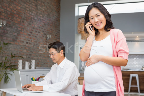 Mosolyog terhes nő telefonbeszélgetés otthon férj dolgozik Stock fotó © wavebreak_media
