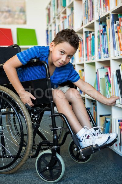 Portret băiat cautare cărţi bibliotecă Imagine de stoc © wavebreak_media