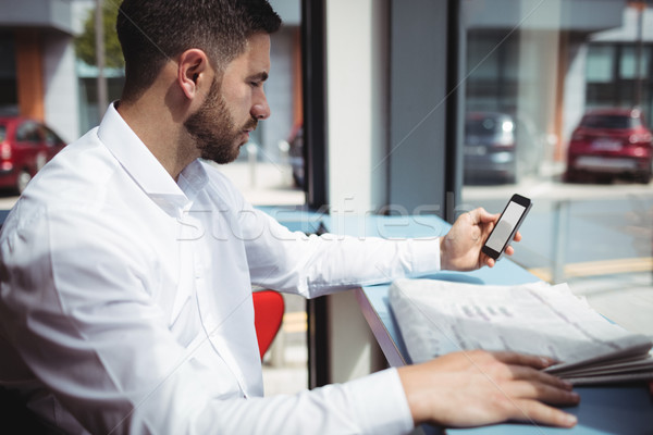 Man using mobile phone while reading newspaper Stock photo © wavebreak_media