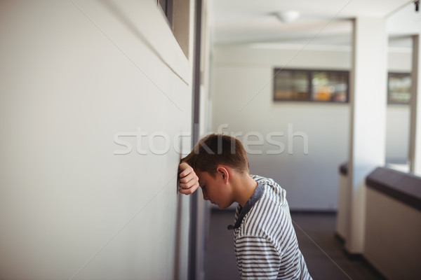 Sad schoolboy leaning head against wall in corridor Stock photo © wavebreak_media