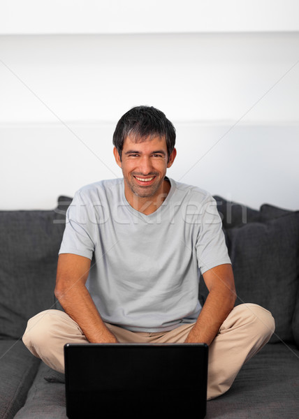 Happy man using a laptop on a grey sofa Stock photo © wavebreak_media