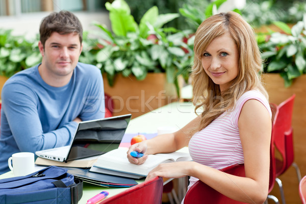 Stock photo: Smiling couple of students working together in the cafeteria of their university