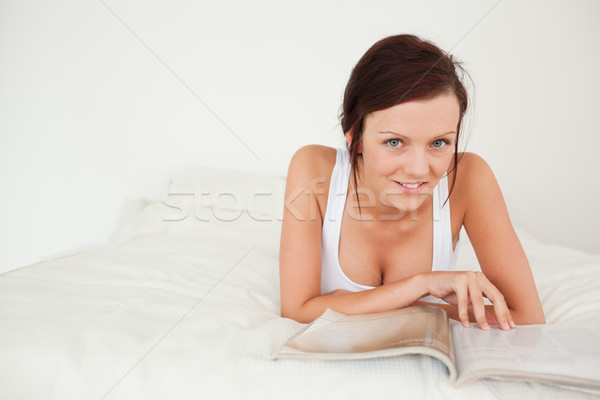 Woman with a magazine looking into the camera in her bedroom Stock photo © wavebreak_media