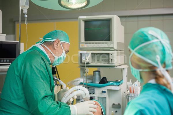 Surgeon holding a mask on the face of a patient in a surgical room Stock photo © wavebreak_media