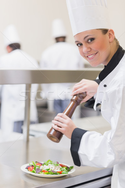 Smiling chef adding pepper to salad in kitchen Stock photo © wavebreak_media