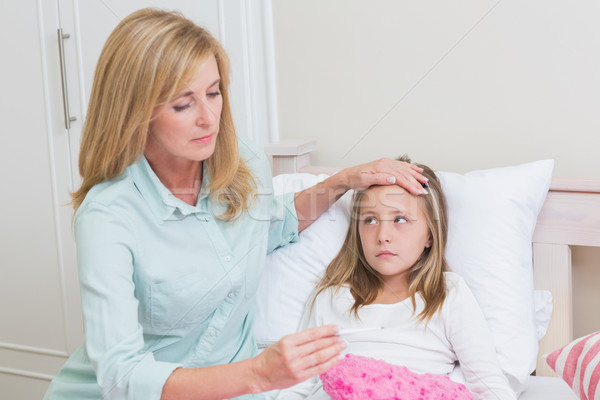 Mother measuring her daughters temperature Stock photo © wavebreak_media