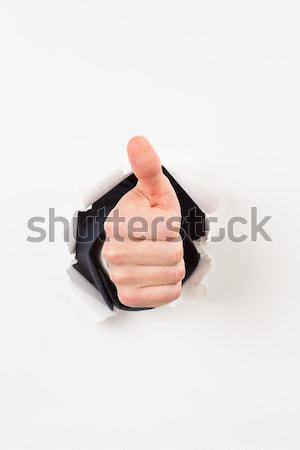 Stock photo: Thumbs up bursting through paper