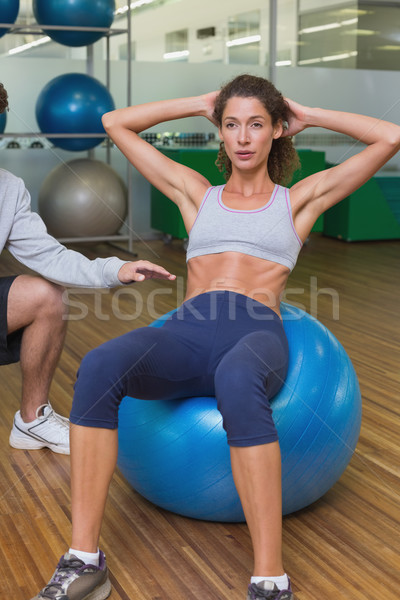 Stock photo: Trainer helping his client doing sit up on exercise ball