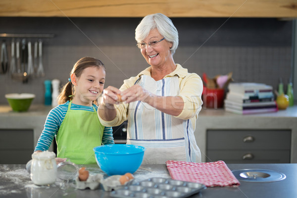 Smiling grandmother showing granddaughter to break eggs Stock photo © wavebreak_media