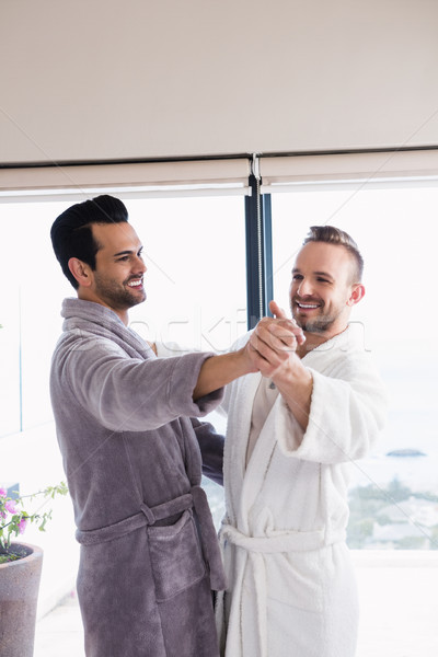 Happy gay couple dancing waltz in bathrobe Stock photo © wavebreak_media