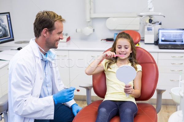 Smiling young patient brushing her teeth in dental clinic Stock photo © wavebreak_media