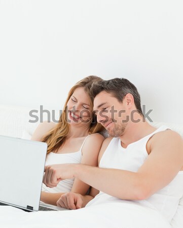 Stock photo: Pretty couple using a laptop in the bedroom