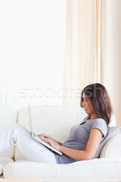 dark-haired woman sitting on sofa while working on notebook Stock photo © wavebreak_media