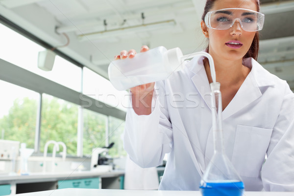 Female science student pouring liquid with protective glasses in a laboratory Stock photo © wavebreak_media