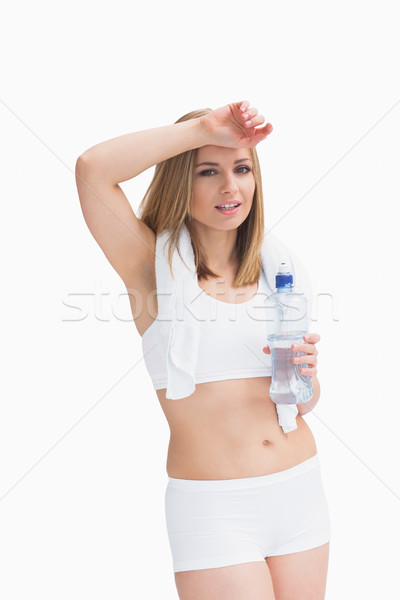 Portrait of sporty woman holding water bottle and wiping sweat w Stock photo © wavebreak_media