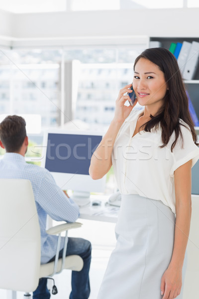 Female artist using mobile phone with colleague in background Stock photo © wavebreak_media
