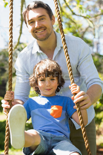 Stock photo: Happy father pushing boy on swing