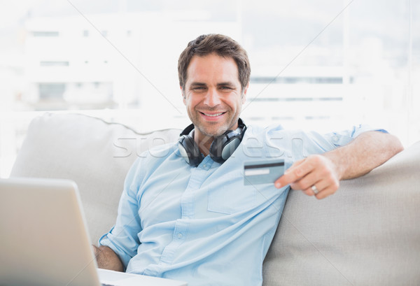 Szczęśliwy przystojny mężczyzna posiedzenia sofa zakupy online laptop Zdjęcia stock © wavebreak_media