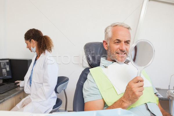 Stock photo: Patient admiring his new smile in the mirror