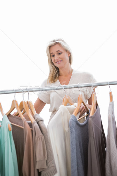 Pretty blonde looking through clothes rail Stock photo © wavebreak_media