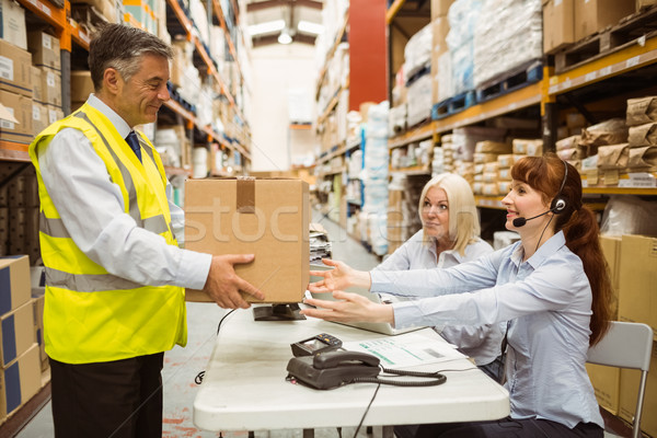 Manager wearing yellow vest giving box to his colleague Stock photo © wavebreak_media
