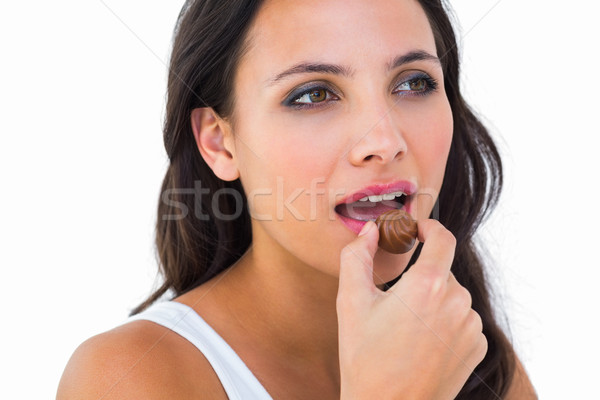 Pretty brunette eating chocolate candy Stock photo © wavebreak_media