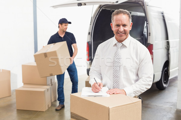 Smiling manager standing behind stack of cardboard boxes Stock photo © wavebreak_media