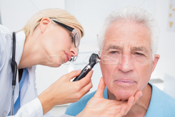 Doctor examining senior patients ear with otoscope Stock photo © wavebreak_media