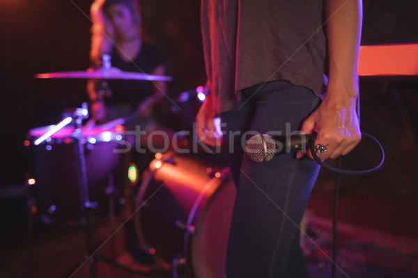 Female singer holding microphone with drummer performing in illuminated nightclub Stock photo © wavebreak_media