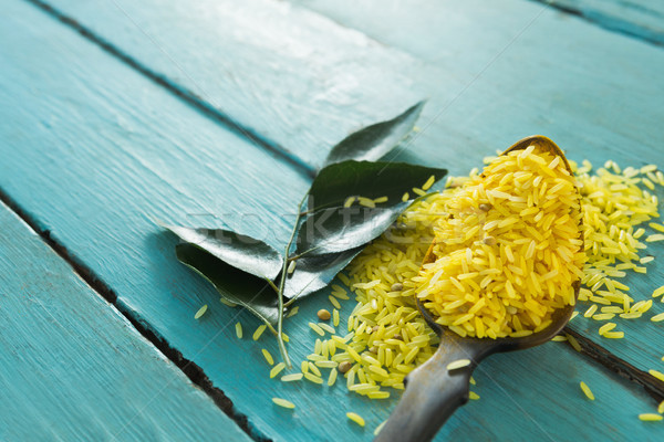 Raw organic yellow rice and curry leaves on wooden table Stock photo © wavebreak_media