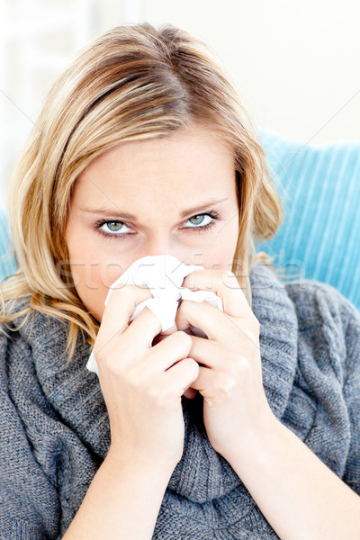 Sick woman using a tissue sitting on a sofa at home Stock photo © wavebreak_media