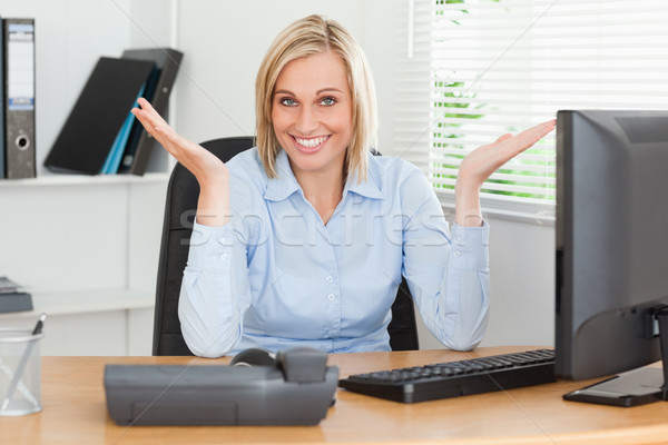 Smiling Blonde Woman Sitting Behind Desk Not Having A Clue What To