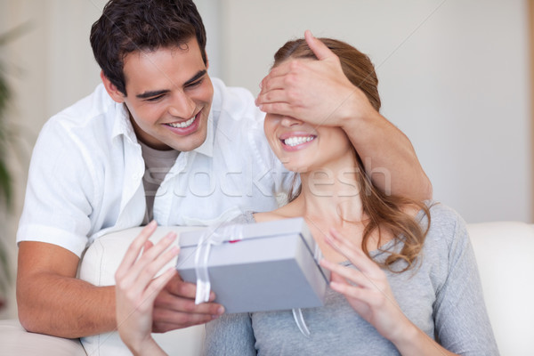 Stock photo: Young man covering the eyes of his girlfriend while giving her a present